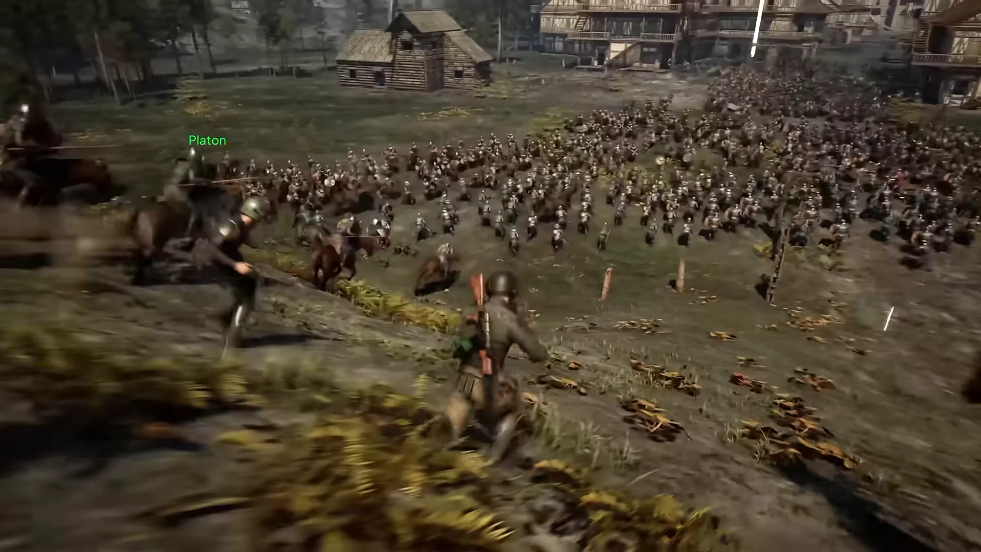 Riders and foot soldiers charge across a field toward a large army in front of timber buildings.