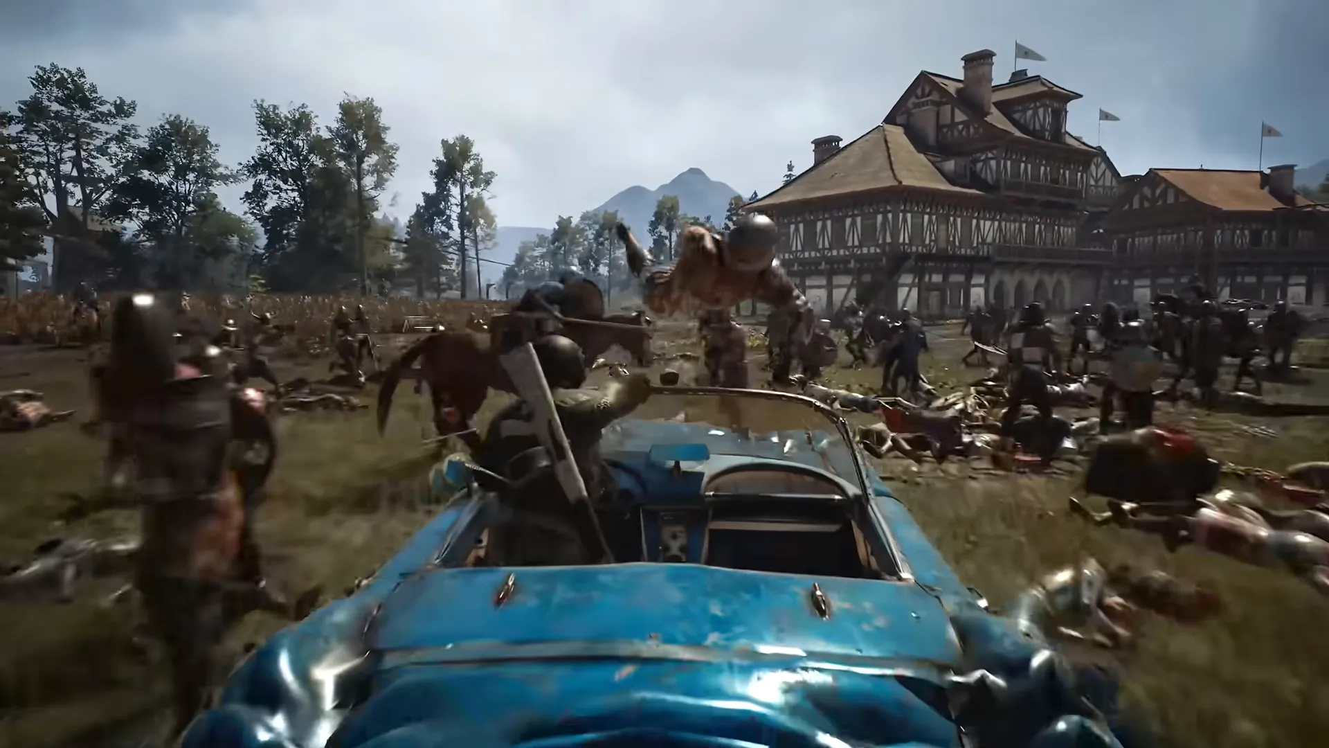 A soldier drives a blue open-top car through a battle in front of a large timber building.
